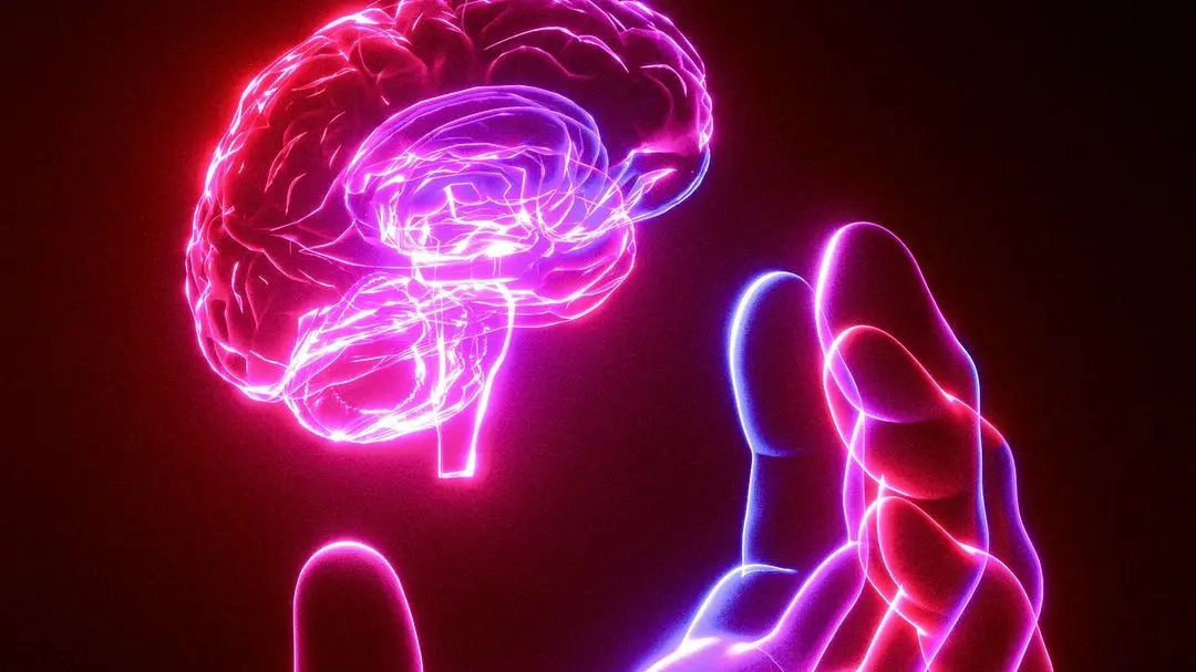 A person's hand holding a glowing brain model